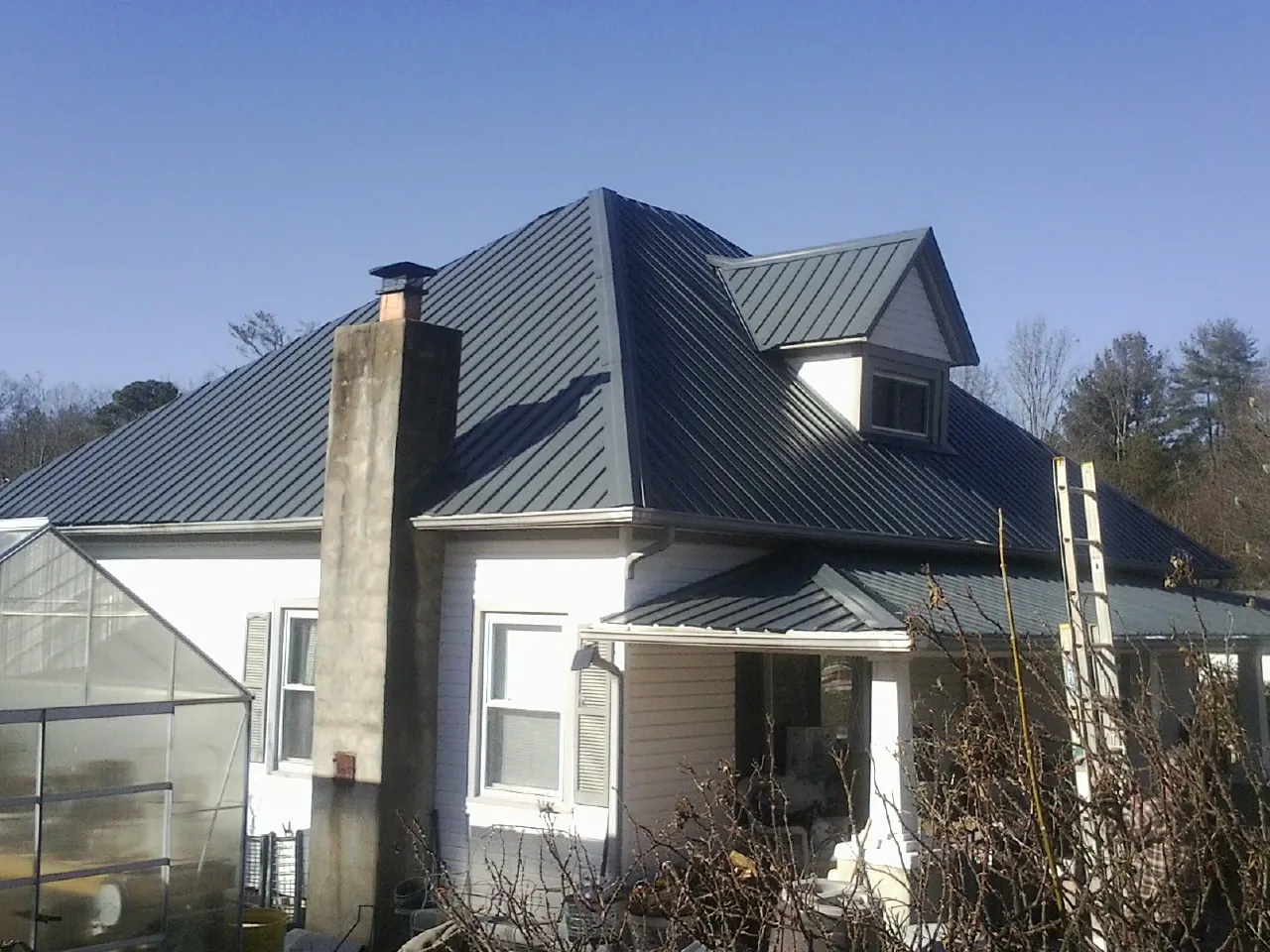 Dark blue standing seam metal roof on a white farmhouse with dormer — Slate & Tile Roof Repair by Roofing Brothers in Gilmanton Iron Works