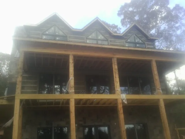 Dormers and porch framing on a large log home under construction — Roof Coating work by our crew in Gilmanton Iron Works