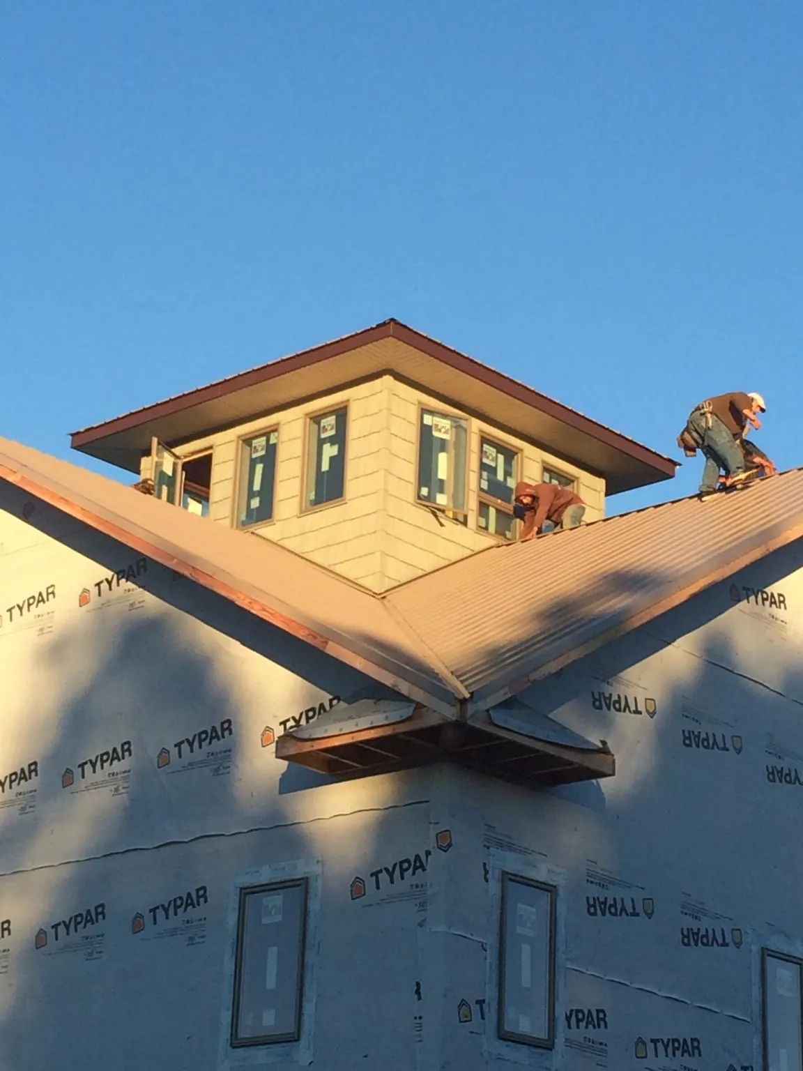 Roofers working around a rooftop cupola on a new metal roof at sunset — Roof Waterproofing in Gilmanton Iron Works by Roofing Brothers